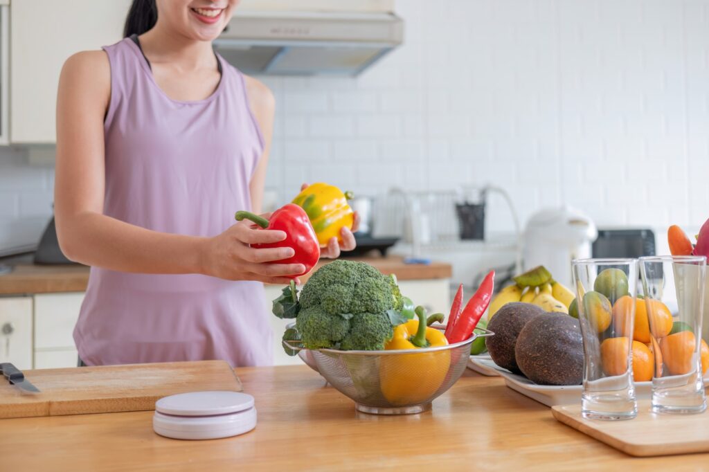 happy young woman cooking healthy vegetarian food at home. Fit smiling housewife or fitness coach in